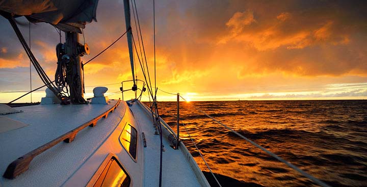 Why Choose LOXX®? The Strength of Self-Locking; White yacht sailing in an open sea at sunset. A view from the deck to the bow, mast, sails. Epic cloudscape. Dramatic sky with glowing golden clouds after the storm. Racing, sport, leisure activity