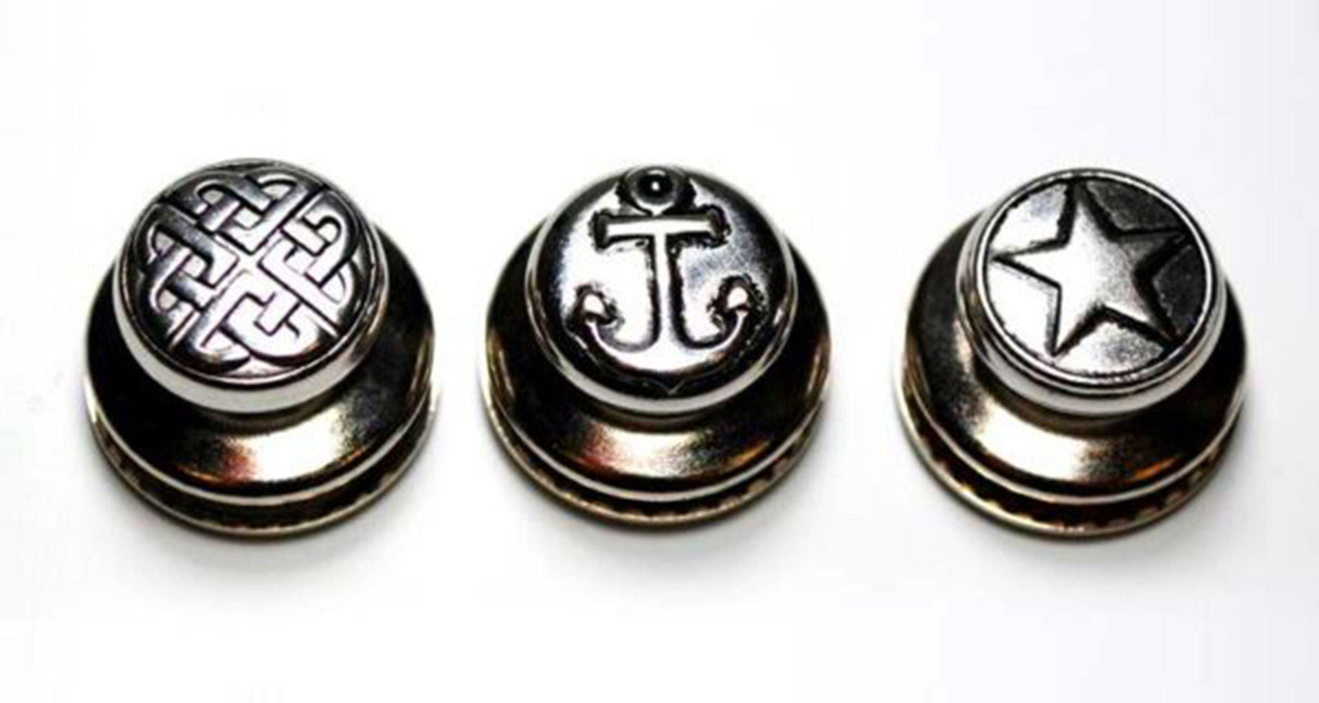 Three engraved metal snap fastener buttons with decorative designs